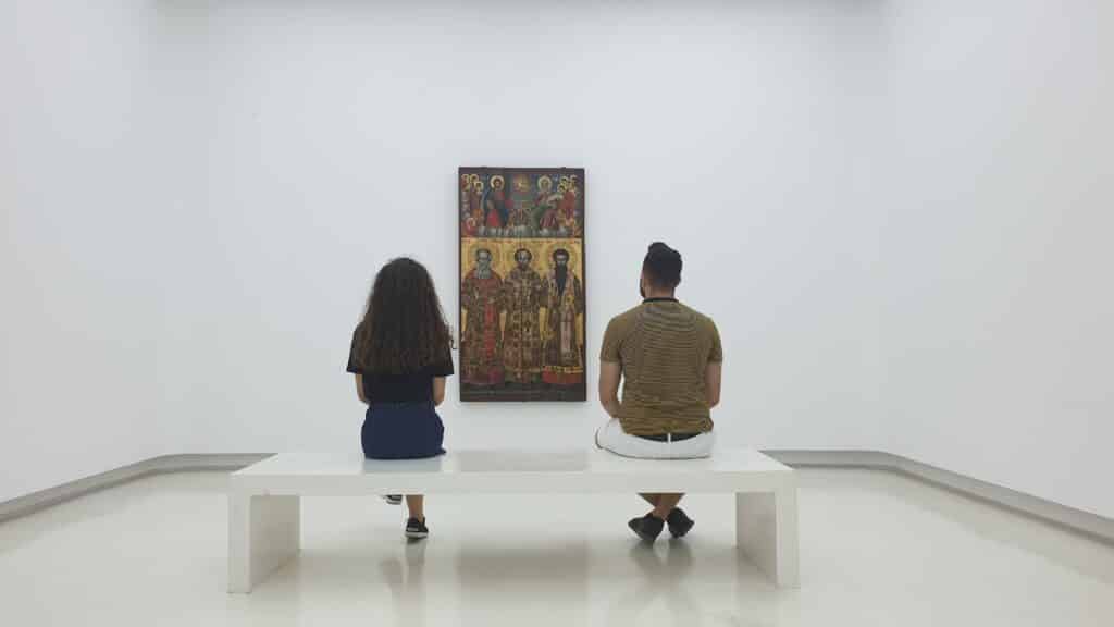 man and woman sitting on a bench in the gallery